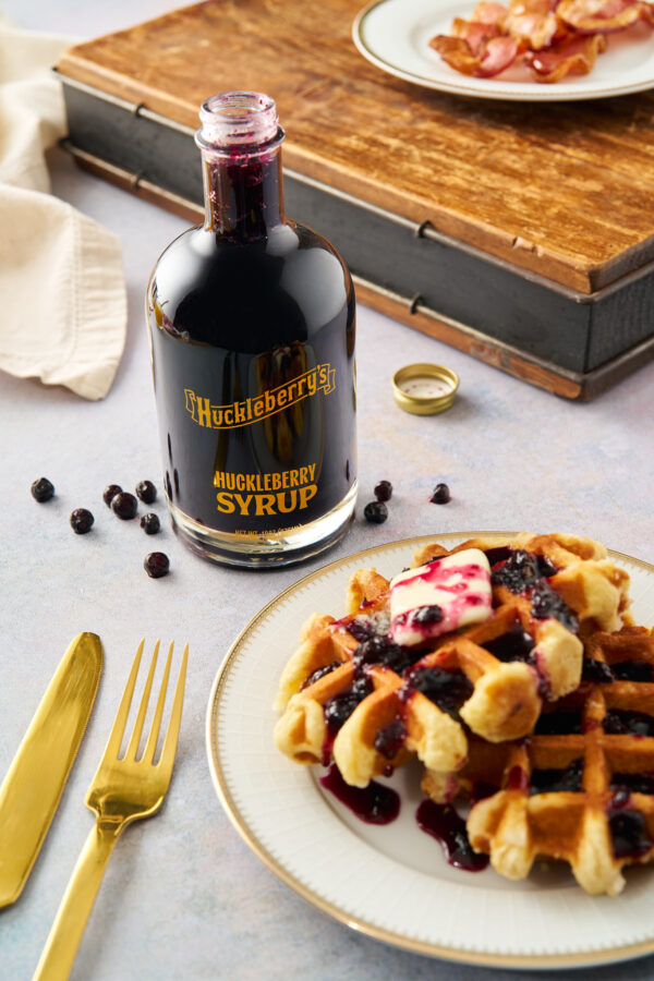 A bottle of huckleberry syrup on a table.